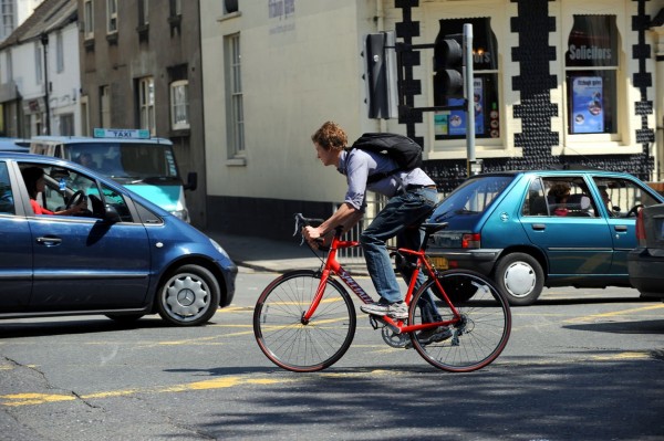 Cyclist in amongst busy traffic in Brighton city centre UK